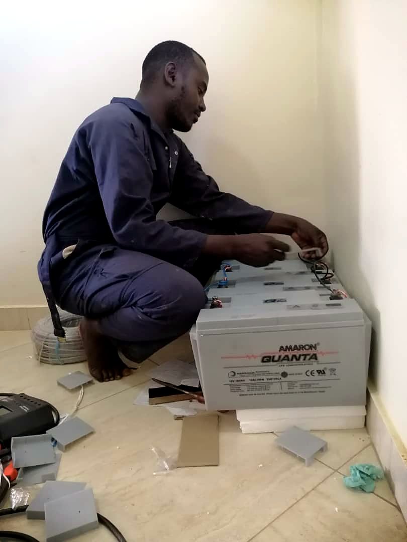 Technician wiring a row of deep-cycle batteries for a backup system