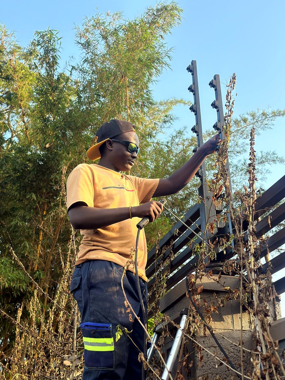 Technician tensioning electric fence wires along a perimeter wall