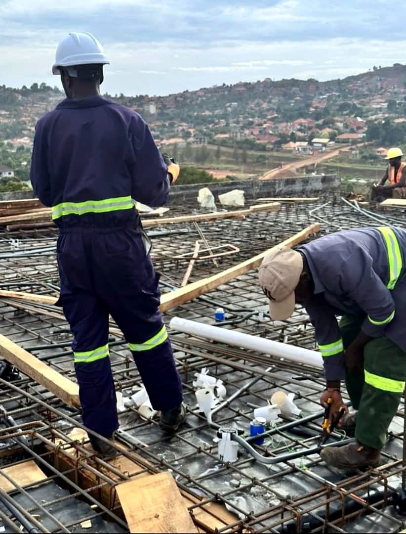 Crew in hard hats laying conduit on reinforcement before a slab is cast