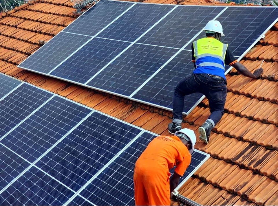Technicians in safety harnesses installing solar panels on a tiled roof