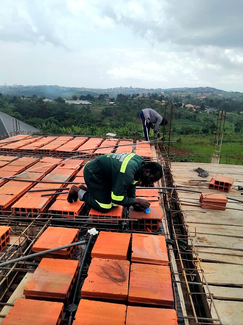Technician laying electrical conduit and boxes in a hollow-block slab before concrete is cast